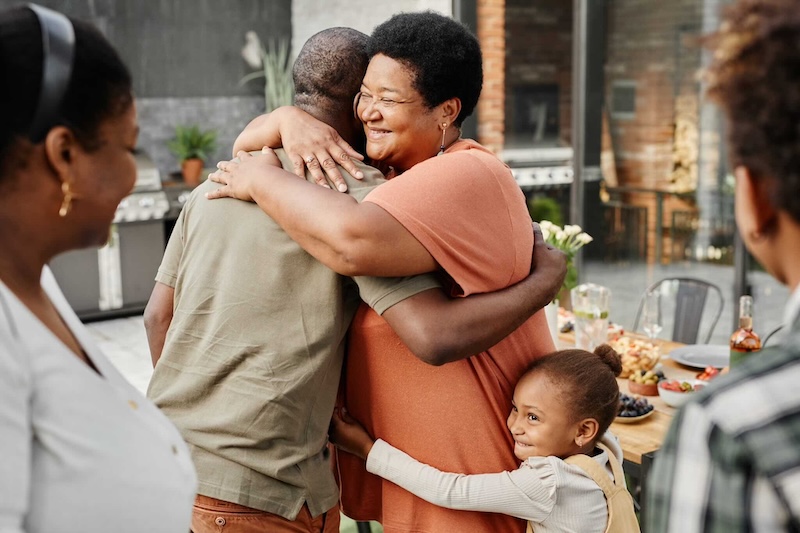 A family hugging in the kitchen of their home.